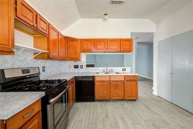 kitchen featuring lofted ceiling, sink, light hardwood / wood-style floors, stainless steel gas range oven, and dishwasher