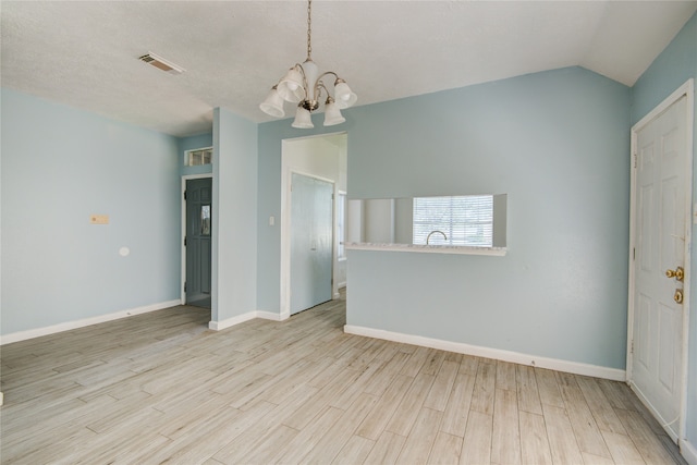 unfurnished room with a notable chandelier, light hardwood / wood-style flooring, vaulted ceiling, and a textured ceiling