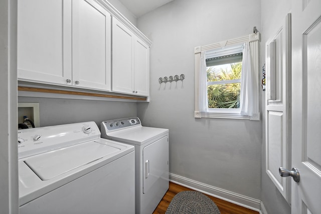 laundry room featuring washing machine and dryer, dark hardwood / wood-style flooring, and cabinets