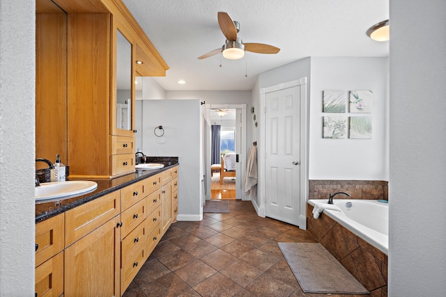 bathroom with ceiling fan, vanity, a relaxing tiled tub, a textured ceiling, and tile patterned flooring