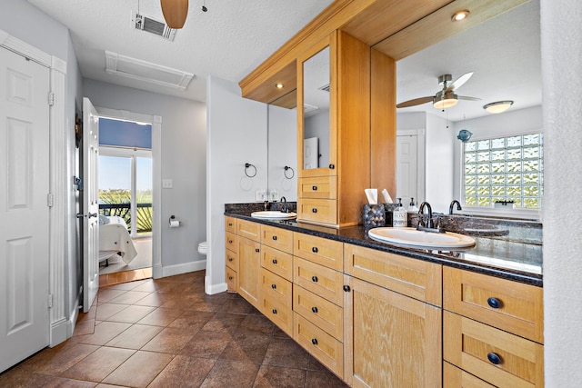 bathroom with a healthy amount of sunlight, toilet, vanity, and a textured ceiling