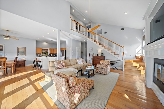 living room featuring light hardwood / wood-style floors, high vaulted ceiling, and ceiling fan