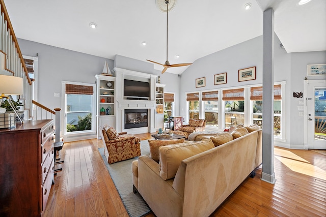 living room with ceiling fan, light wood-type flooring, high vaulted ceiling, and a healthy amount of sunlight