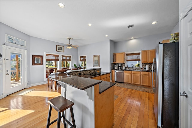 kitchen with a kitchen island, a kitchen bar, stainless steel appliances, and light hardwood / wood-style flooring