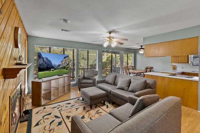 266 Water Ridge Dr, Livingston, TX 77351 - living area with light wood finished floors, a ceiling fan, and a lit fireplace