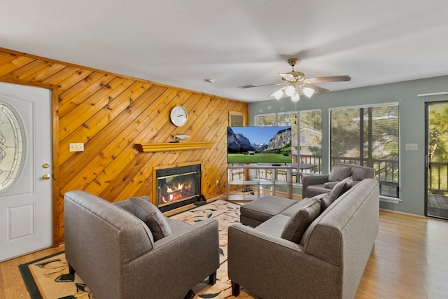 266 Water Ridge Dr, Livingston, TX 77351 - living room with a glass covered fireplace, wooden walls, a ceiling fan, and wood finished floors
