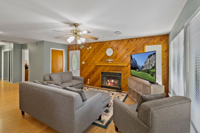 266 Water Ridge Dr, Livingston, TX 77351 - living room featuring a glass covered fireplace, ceiling fan, light wood-style floors, and wood walls