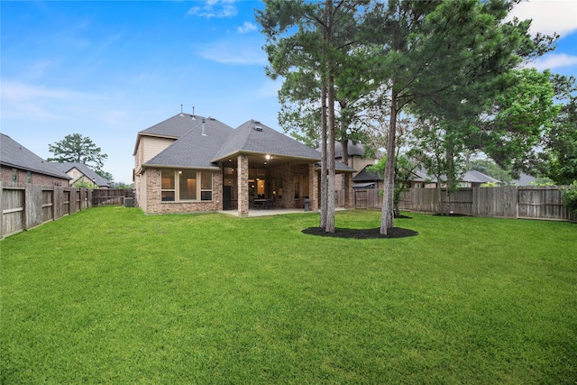 back of house with a yard and a patio