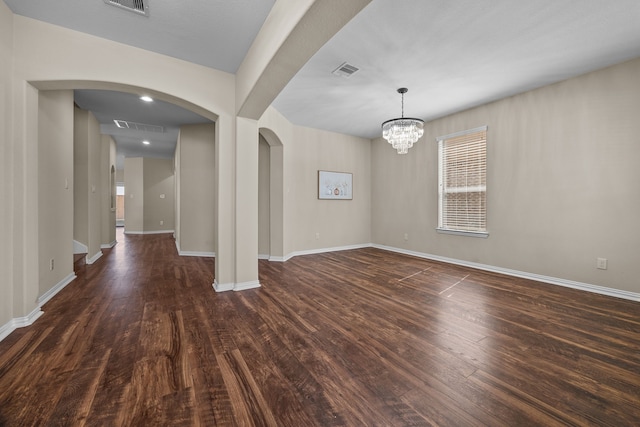 unfurnished room with a notable chandelier and dark hardwood / wood-style floors