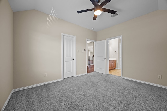 unfurnished bedroom featuring connected bathroom, ceiling fan, vaulted ceiling, and light colored carpet