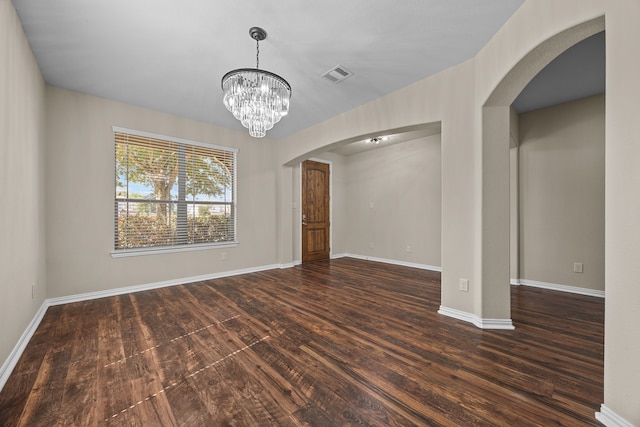 empty room with a chandelier and dark hardwood / wood-style flooring