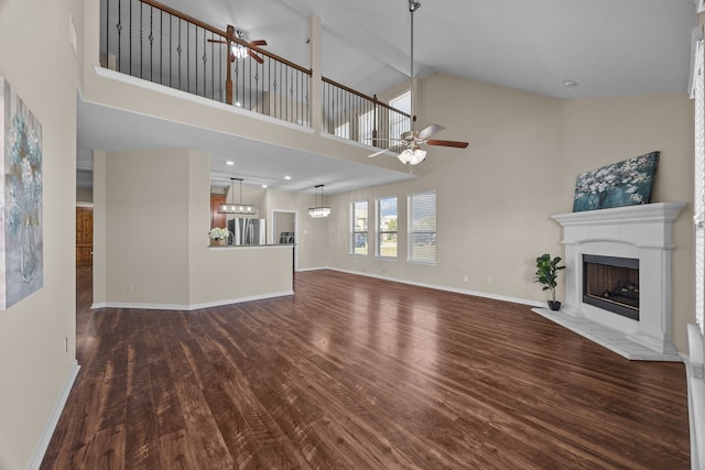 unfurnished living room with dark wood-type flooring, ceiling fan with notable chandelier, high vaulted ceiling, and beam ceiling