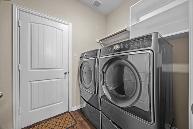 laundry area featuring washing machine and clothes dryer and dark hardwood / wood-style floors