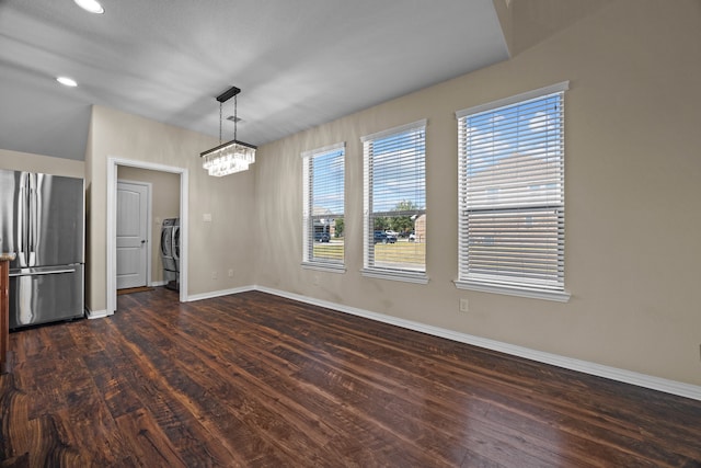 unfurnished dining area featuring a chandelier, dark hardwood / wood-style flooring, and washer / dryer