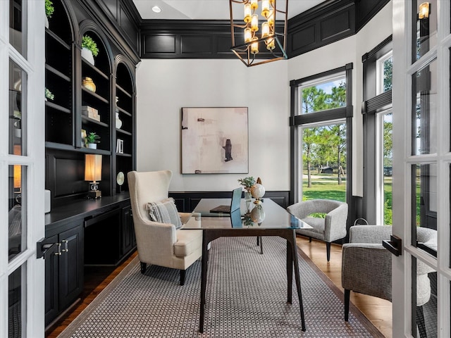 living area featuring french doors, dark hardwood / wood-style floors, a high ceiling, and an inviting chandelier