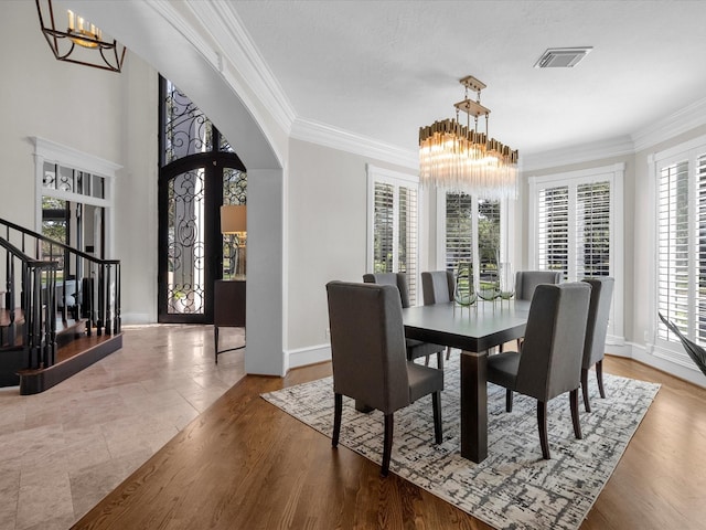 dining space featuring hardwood / wood-style flooring, crown molding, and a chandelier