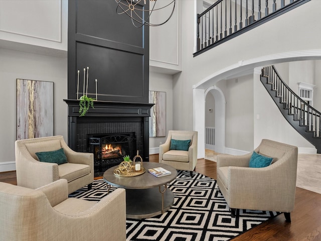 living room featuring a chandelier, a high ceiling, and dark wood-type flooring