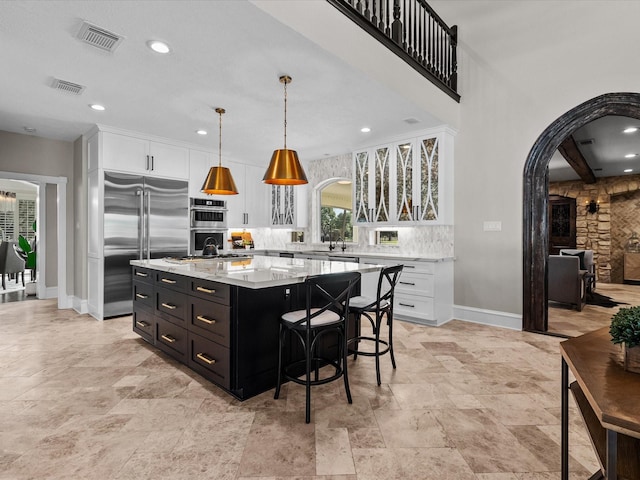 kitchen featuring a kitchen breakfast bar, stainless steel appliances, decorative light fixtures, a center island, and white cabinetry