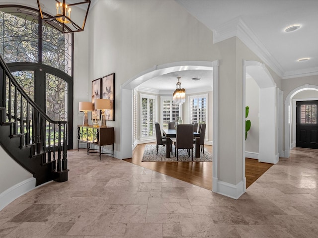 foyer entrance featuring french doors, a high ceiling, crown molding, and a notable chandelier