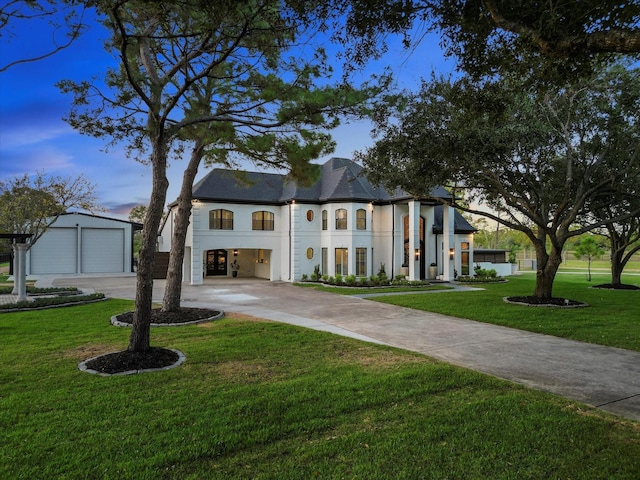 french provincial home with a garage, an outbuilding, stucco siding, and a front yard