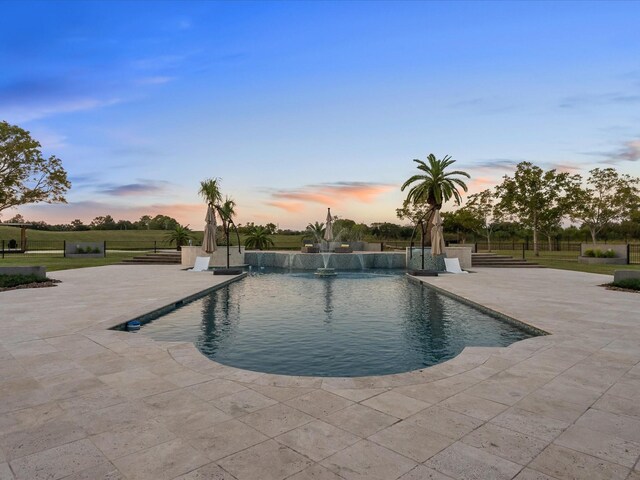 pool at dusk with a patio area