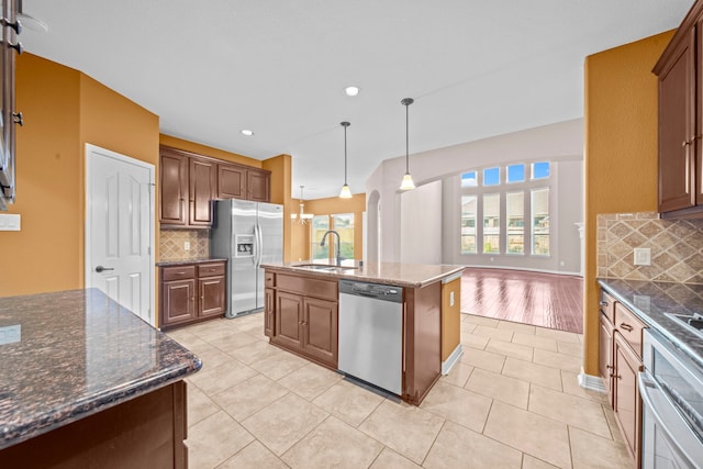 kitchen featuring sink, a kitchen island with sink, stainless steel appliances, and a healthy amount of sunlight