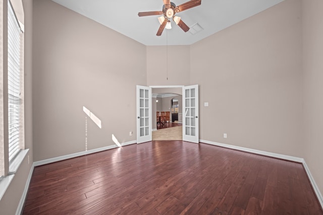 unfurnished room featuring a towering ceiling, french doors, dark wood-type flooring, and ceiling fan