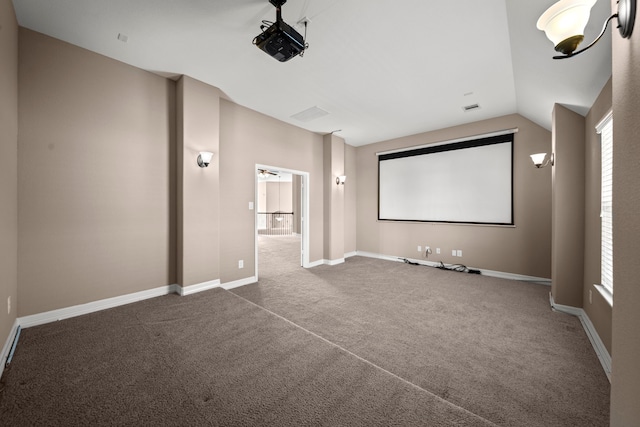 home theater featuring vaulted ceiling and dark carpet