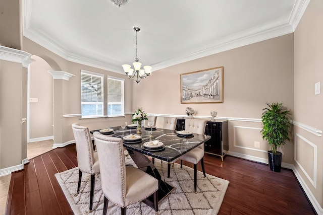 dining room with decorative columns, a chandelier, crown molding, and dark hardwood / wood-style flooring