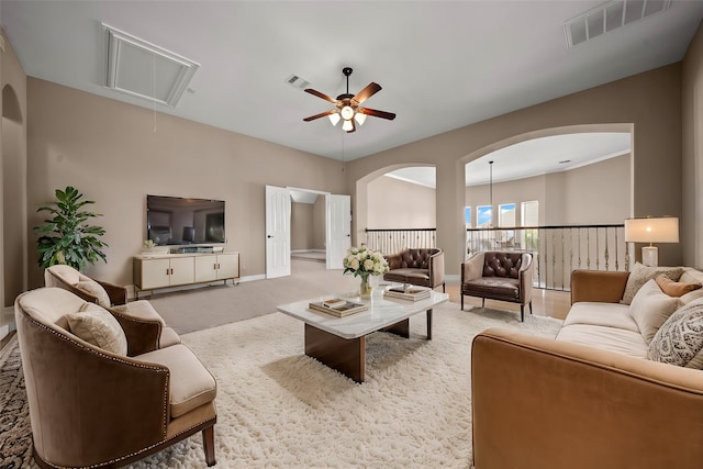 carpeted living room featuring ceiling fan with notable chandelier