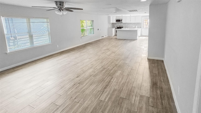 7120 Ave O, Houston, TX 77011 - unfurnished living room featuring baseboards, ceiling fan, and light wood-style flooring