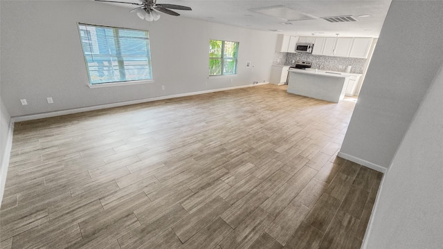 7120 Ave O, Houston, TX 77011 - unfurnished living room with baseboards, ceiling fan, light wood finished floors, and visible vents