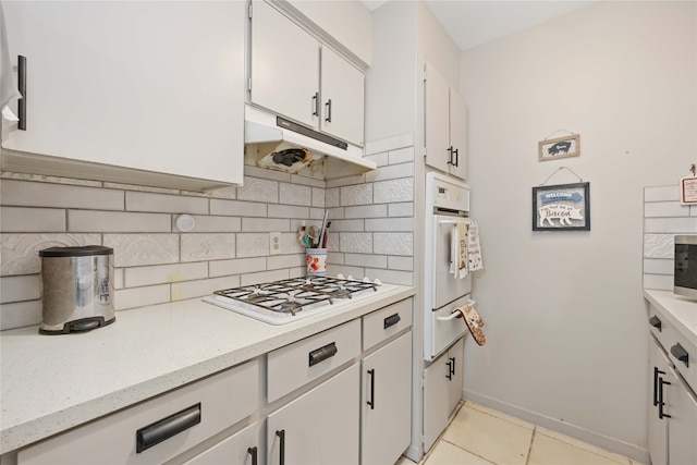 kitchen featuring tasteful backsplash, white appliances, white cabinets, and light tile patterned floors