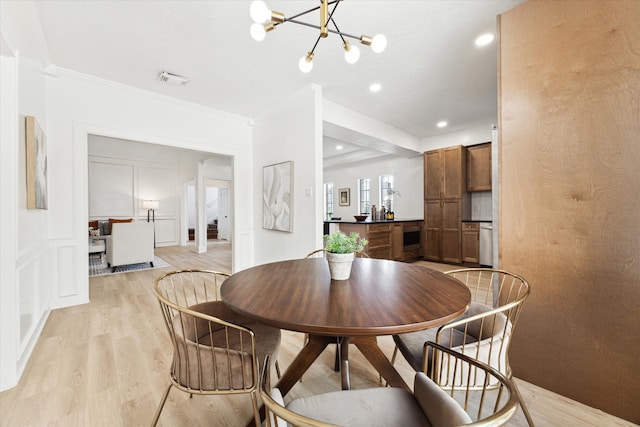 dining room with ornamental molding, a notable chandelier, and light wood-type flooring