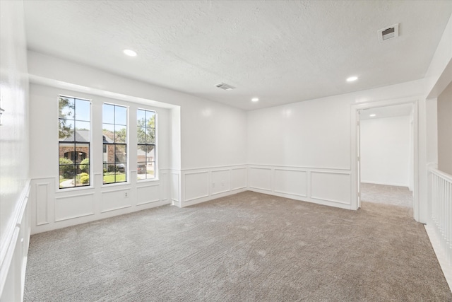 carpeted empty room featuring a textured ceiling