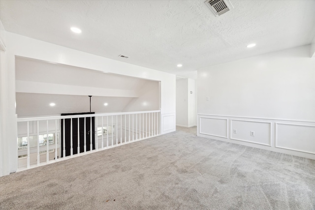 carpeted empty room featuring a textured ceiling