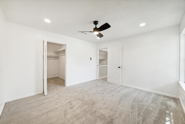 unfurnished bedroom featuring ceiling fan, a closet, light carpet, and a spacious closet