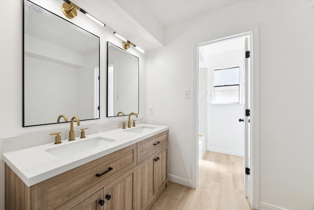 bathroom with wood-type flooring, vanity, and a tub