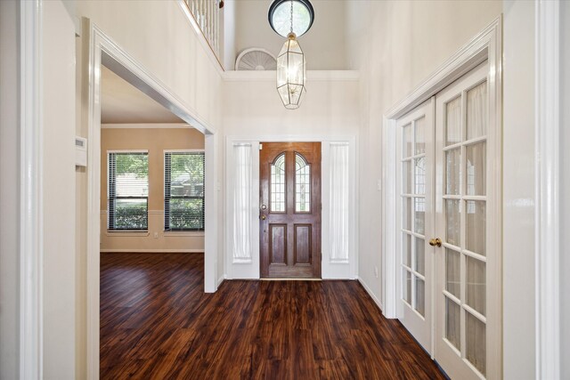 foyer entrance featuring a high ceiling, an inviting chandelier, ornamental molding, and dark hardwood / wood-style flooring