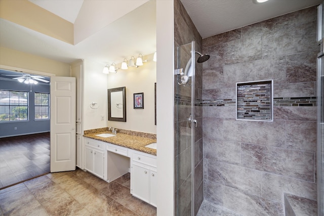 bathroom with ceiling fan, a tile shower, hardwood / wood-style floors, vaulted ceiling, and vanity