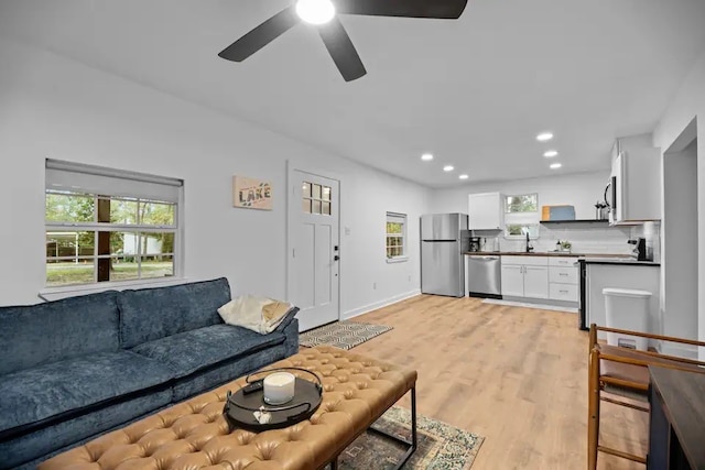 living room featuring light hardwood / wood-style floors, sink, and ceiling fan