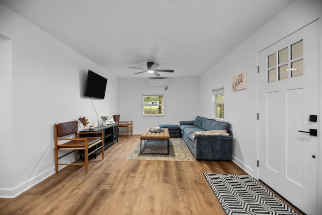 living room featuring a wall unit AC, wood-type flooring, and ceiling fan