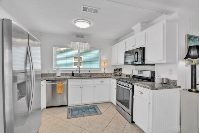 kitchen with stainless steel appliances, ornamental molding, sink, light tile patterned floors, and white cabinets