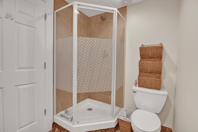 bathroom featuring a shower with door and toilet