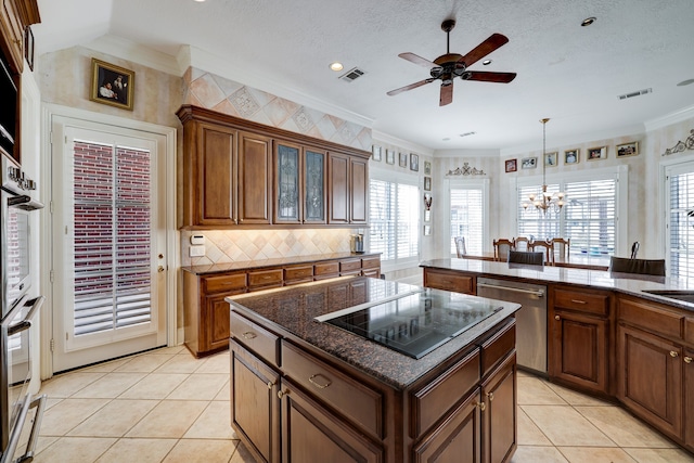 kitchen with a kitchen island, ornamental molding, appliances with stainless steel finishes, light tile patterned floors, and a textured ceiling