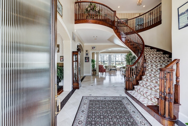 entryway with ornate columns, crown molding, and a high ceiling