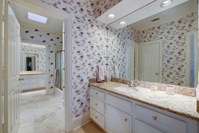 bathroom featuring a skylight, vanity, and a shower with shower door