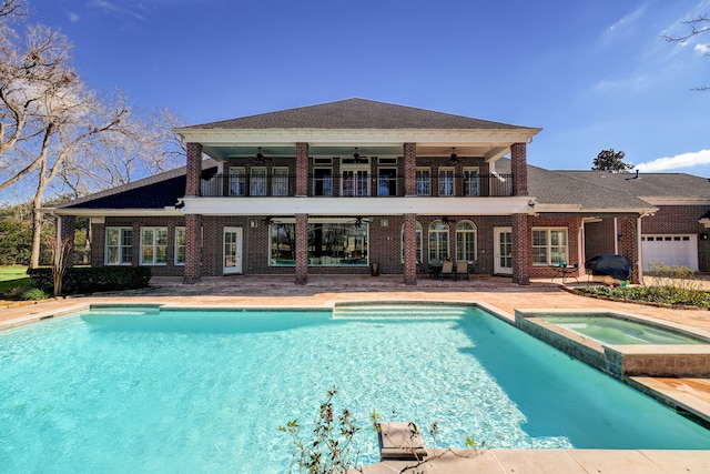 back of property with ceiling fan, a balcony, a patio, and a swimming pool with hot tub