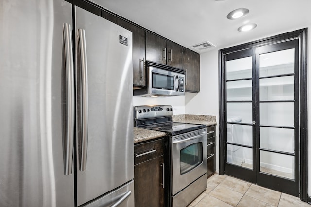 kitchen with dark brown cabinetry, light tile patterned flooring, and appliances with stainless steel finishes