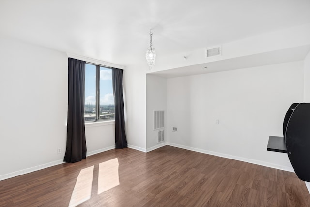 unfurnished room featuring a notable chandelier and dark hardwood / wood-style flooring